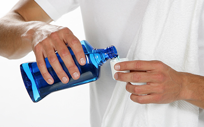 A man pouring blue mouthwash into a cup