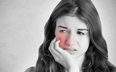 A woman holding her jaw in pain