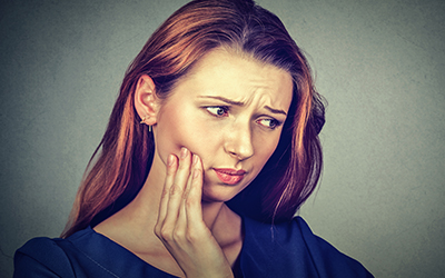 A young women with tooth pain problem who is holding the side of her mouth