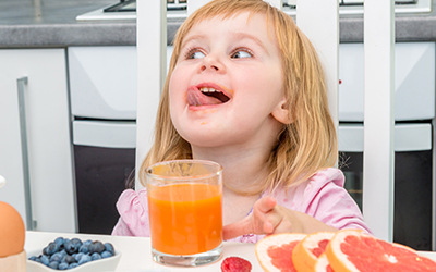 A young child drinking a glass of juice