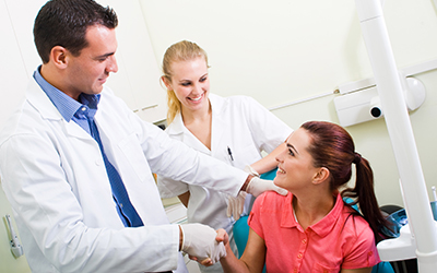 A woman in dental chair talking with a dentist